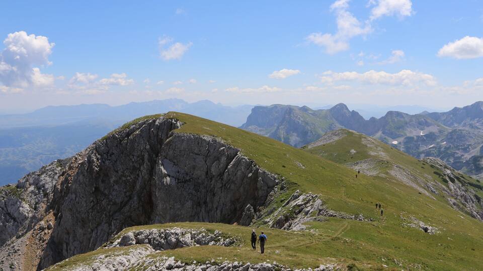 A mountainous landscape with rocky cliffs and grassy slopes.