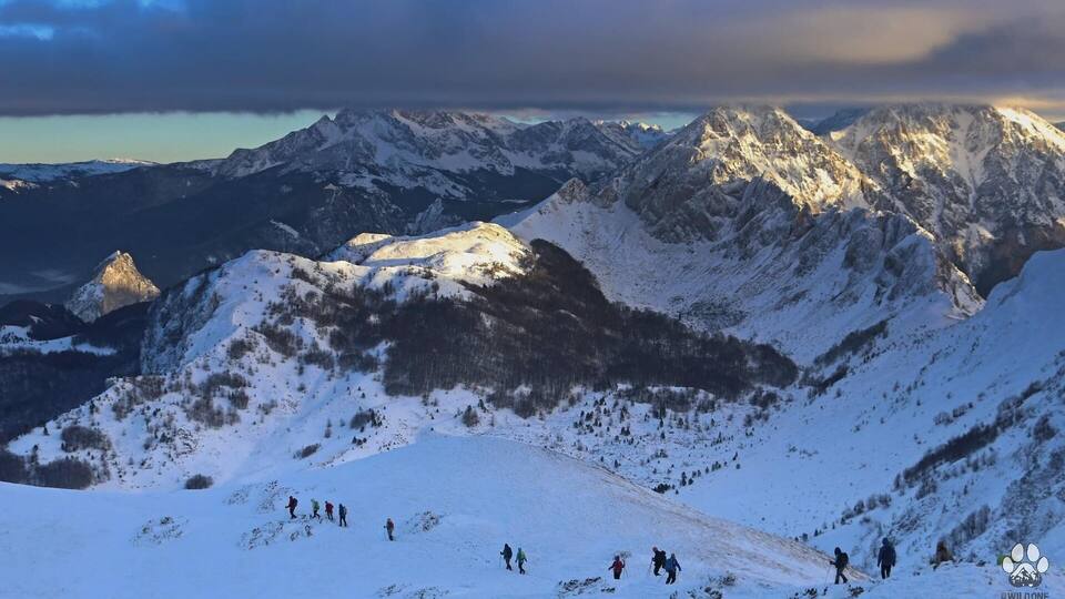 A snowy mountain landscape with hikers.