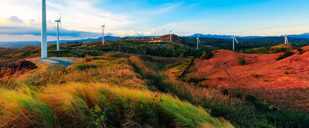 A landscape with multiple wind turbines on rolling hills under a clear blue sky.