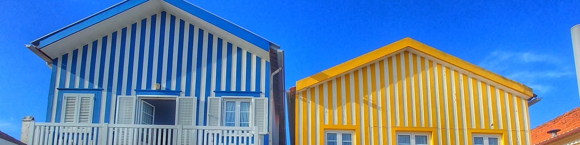 Dois edifícios coloridos com varandas e cercas brancas.