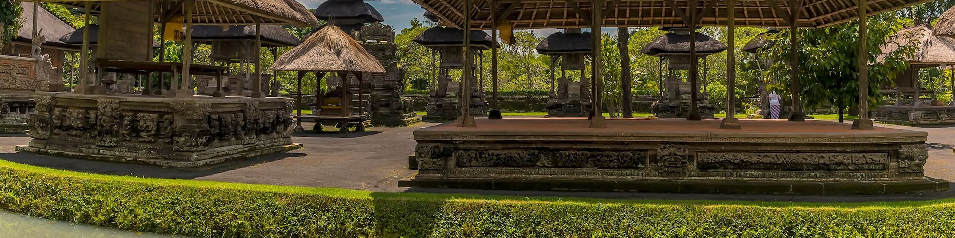 A temple complex with thatched-roof structures and stone carvings.