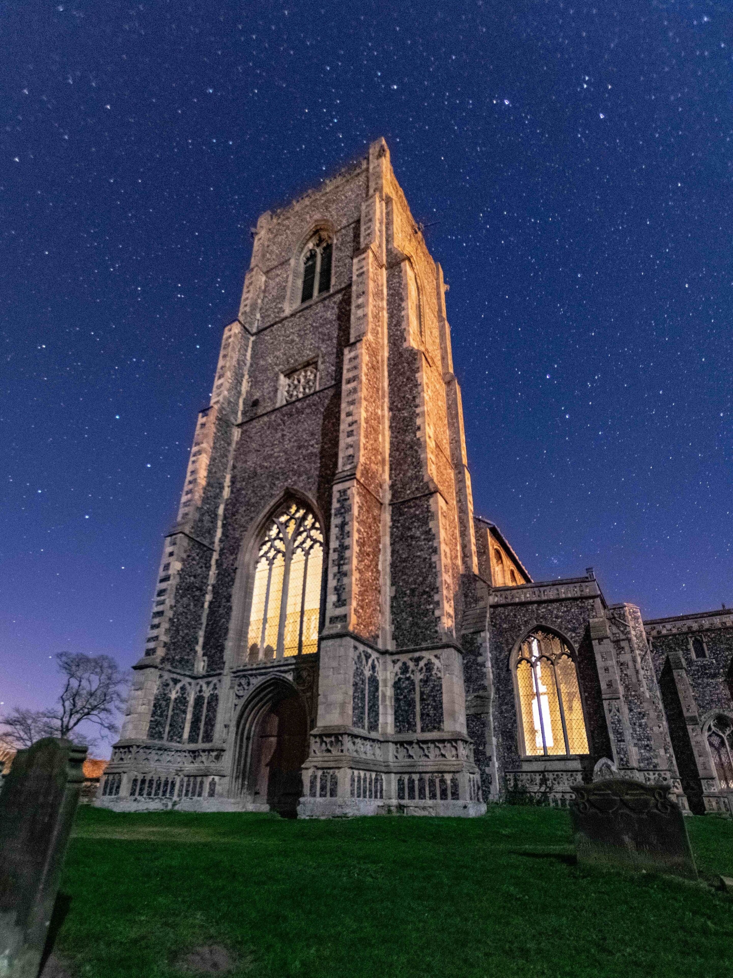 A historic church with tall towers and large arched windows, set against a starry night sky.