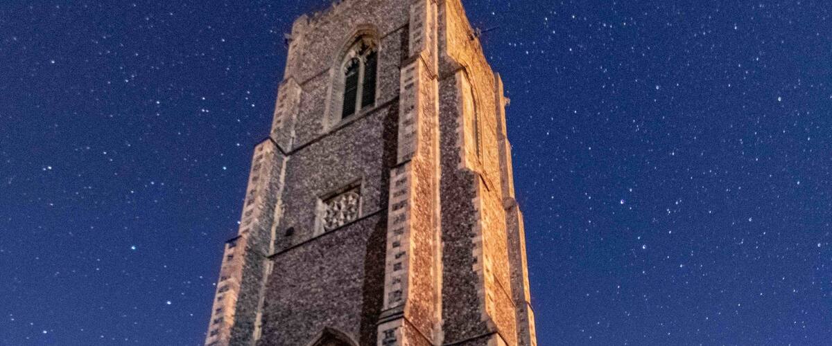 A historic church with tall towers and large arched windows, set against a starry night sky.