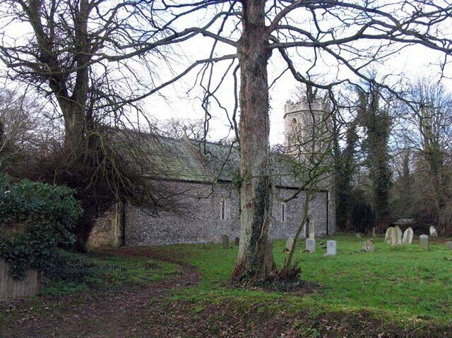 A cemetery with headstones, a stone wall, and a large tree.