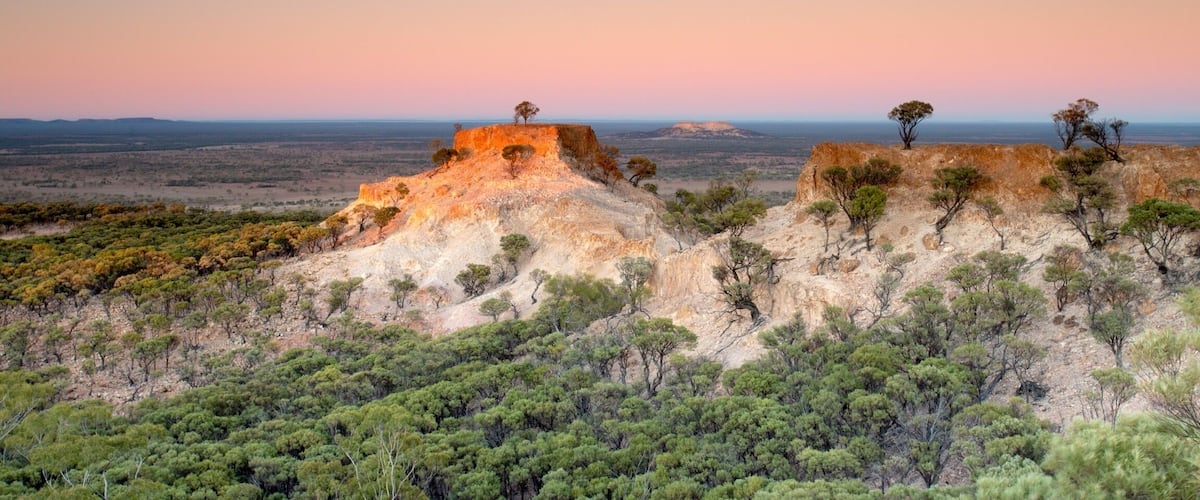 A desert landscape with rocky outcrops and sparse vegetation.