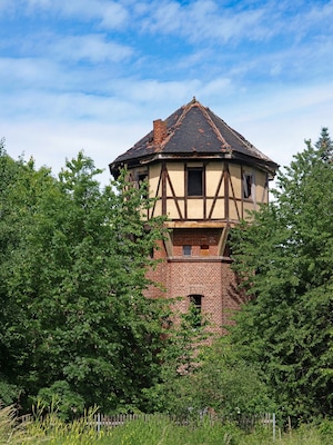 A traditional half-timbered tower house surrounded by lush greenery.