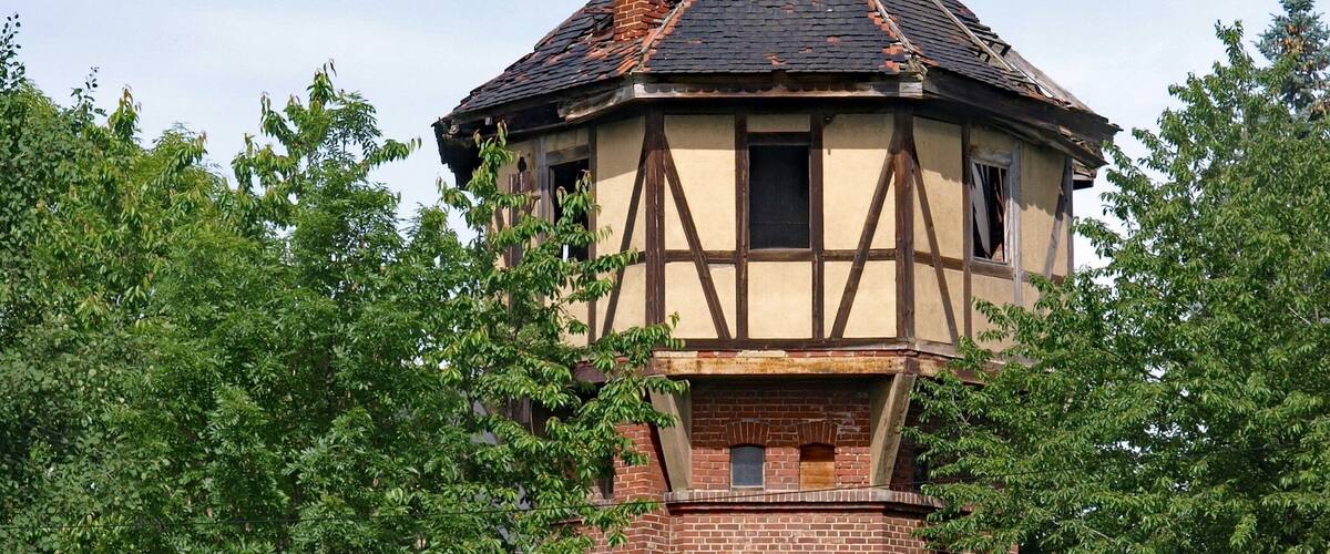 A traditional half-timbered tower house surrounded by lush greenery.