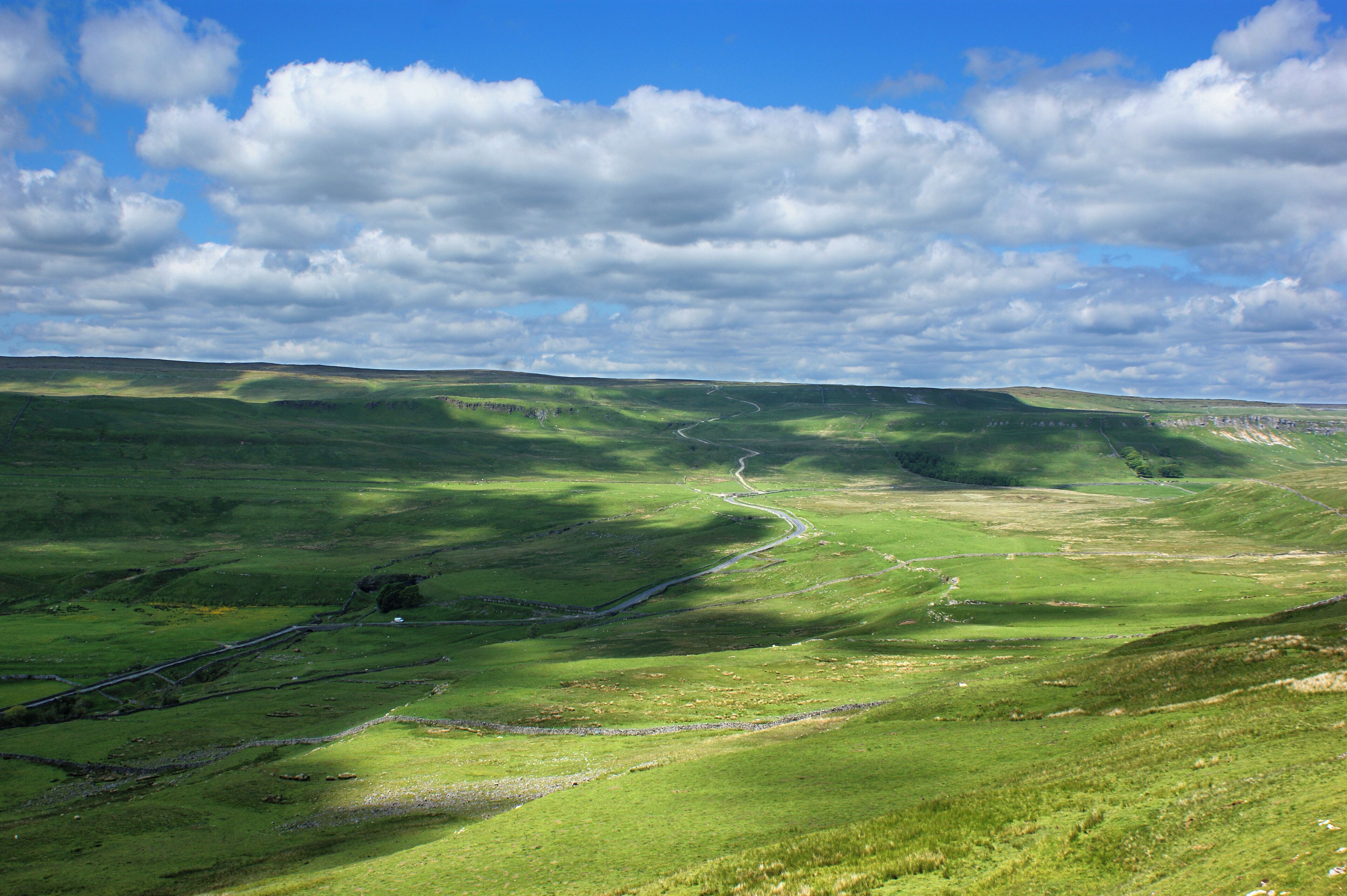 A green valley with a winding road and a river.