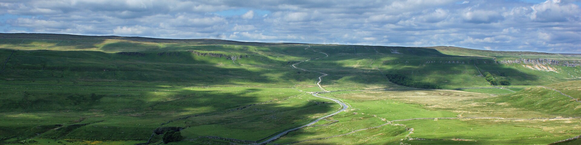 A green valley with a winding road and a river.