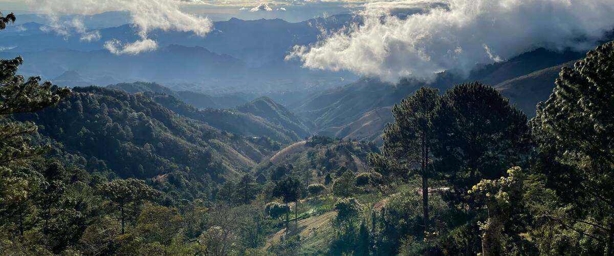 A mountainous landscape with dense forests and a valley.