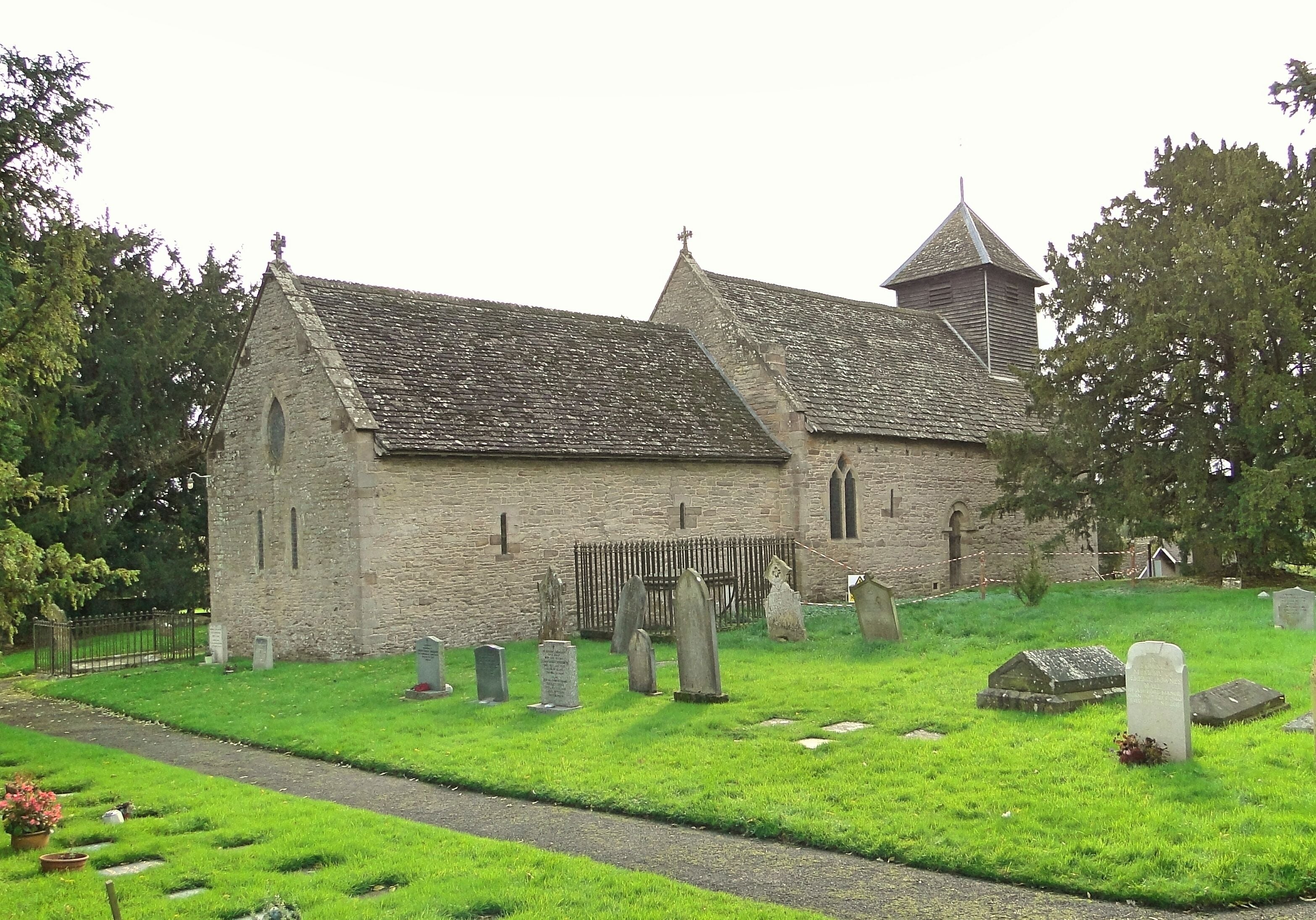 A church with a stone facade, a bell tower, and a cemetery with headstones.