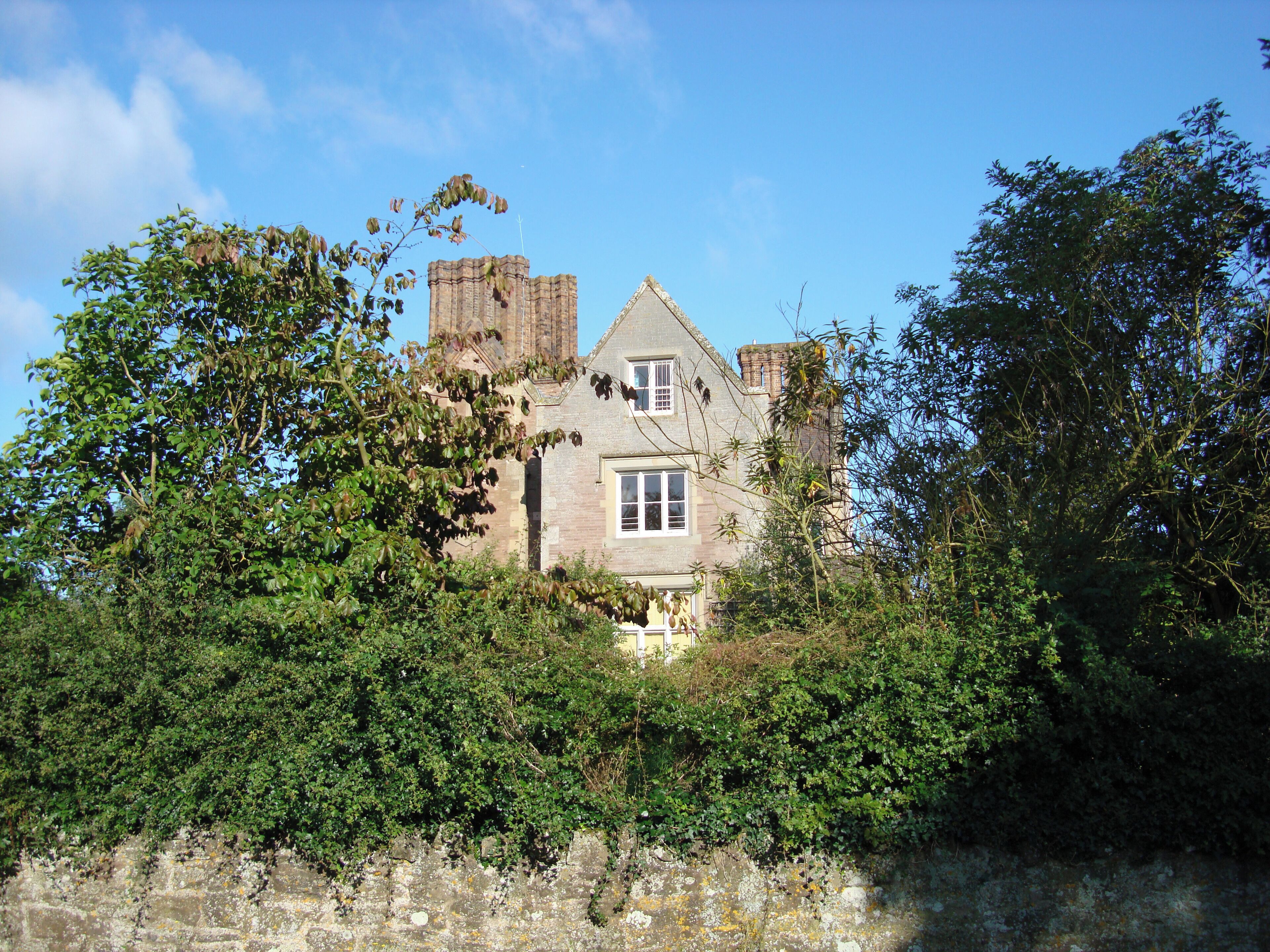 A historic stone house with a large window and a turret.