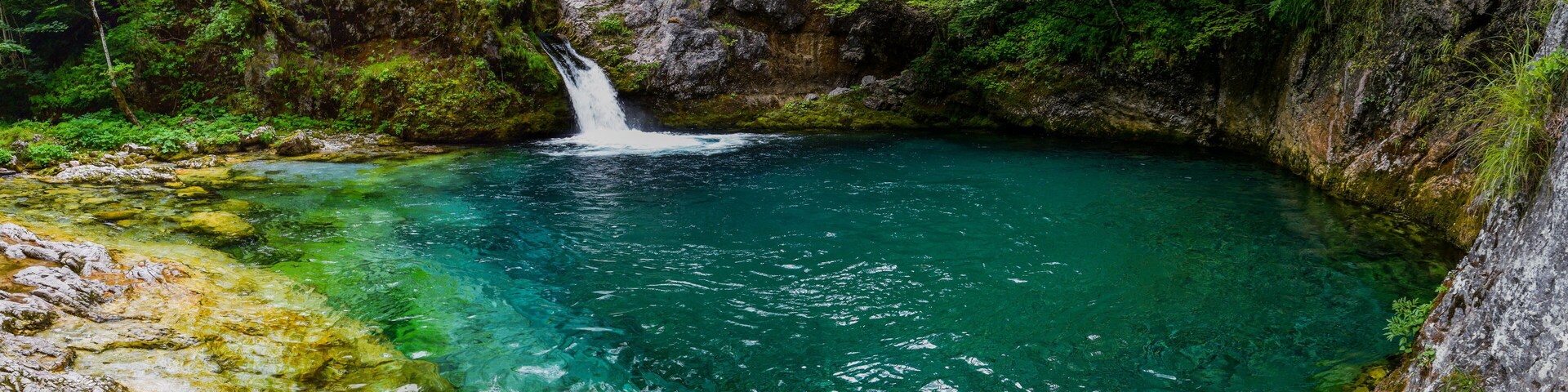 Uma cascata numa área arborizada com águas azul-claras.
