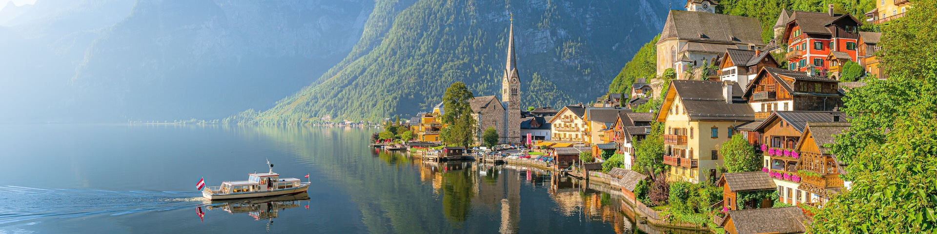 Un lac avec un bateau, une église et des maisons colorées sur une colline.