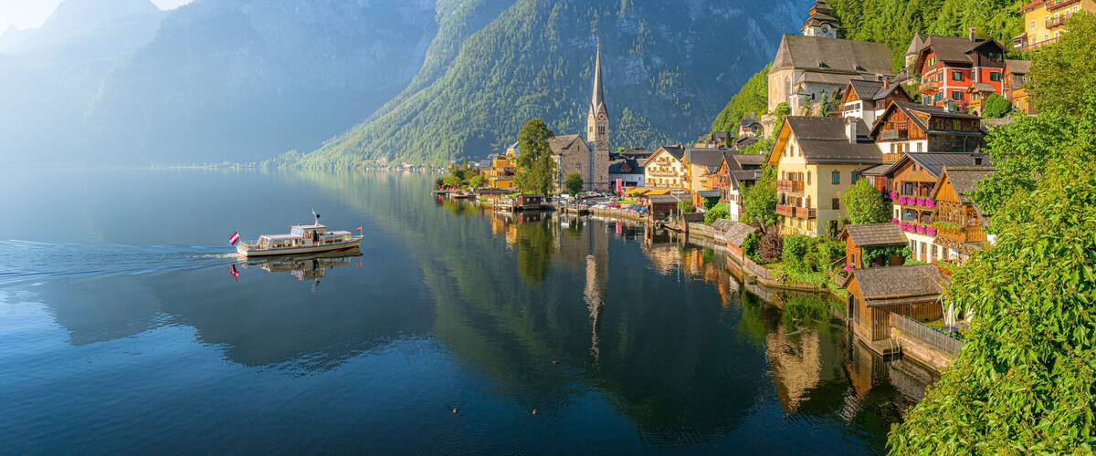 A lake with a boat, a church, and colorful houses on a hillside.