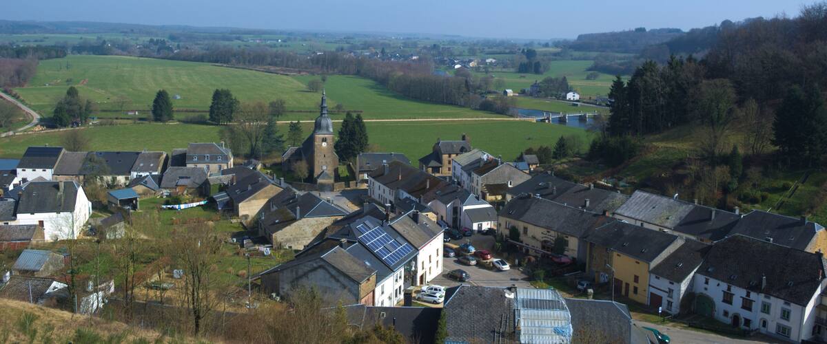 A village with a prominent church tower, surrounded by houses and fields.