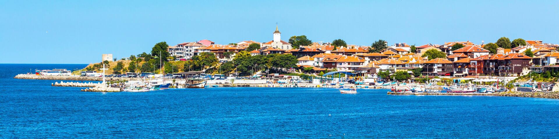 A coastal town with a prominent church tower, waterfront buildings, and a marina with boats.