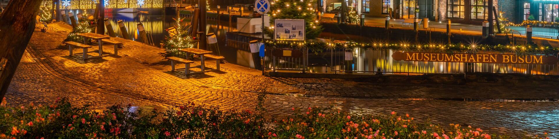 View of of festive lighting and Christmas romantic atmosphere in the Büsum at night. Nighttime view of Büsum at Christmas time. Maritime Christmas city. Signboard "Museum harbour Buesum".