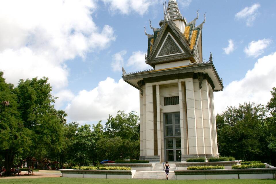 Ett traditionellt tempel med ett gyllene tak och detaljerade sniderier, omgivet av frodig grönska och en klar himmel.