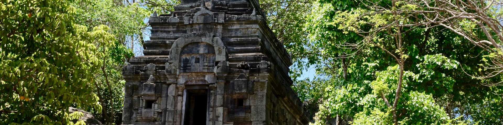 Un antiguo templo de piedra rodeado de exuberante vegetación.