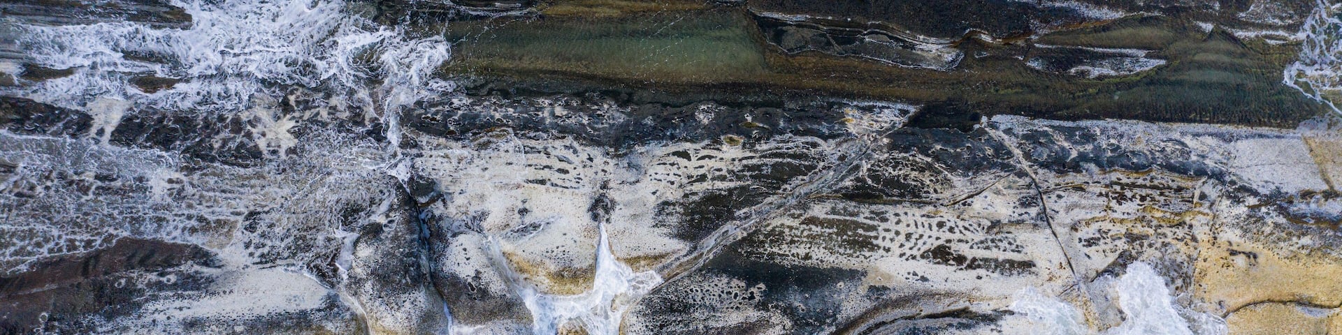 A rocky coastline with waves crashing against the shore.