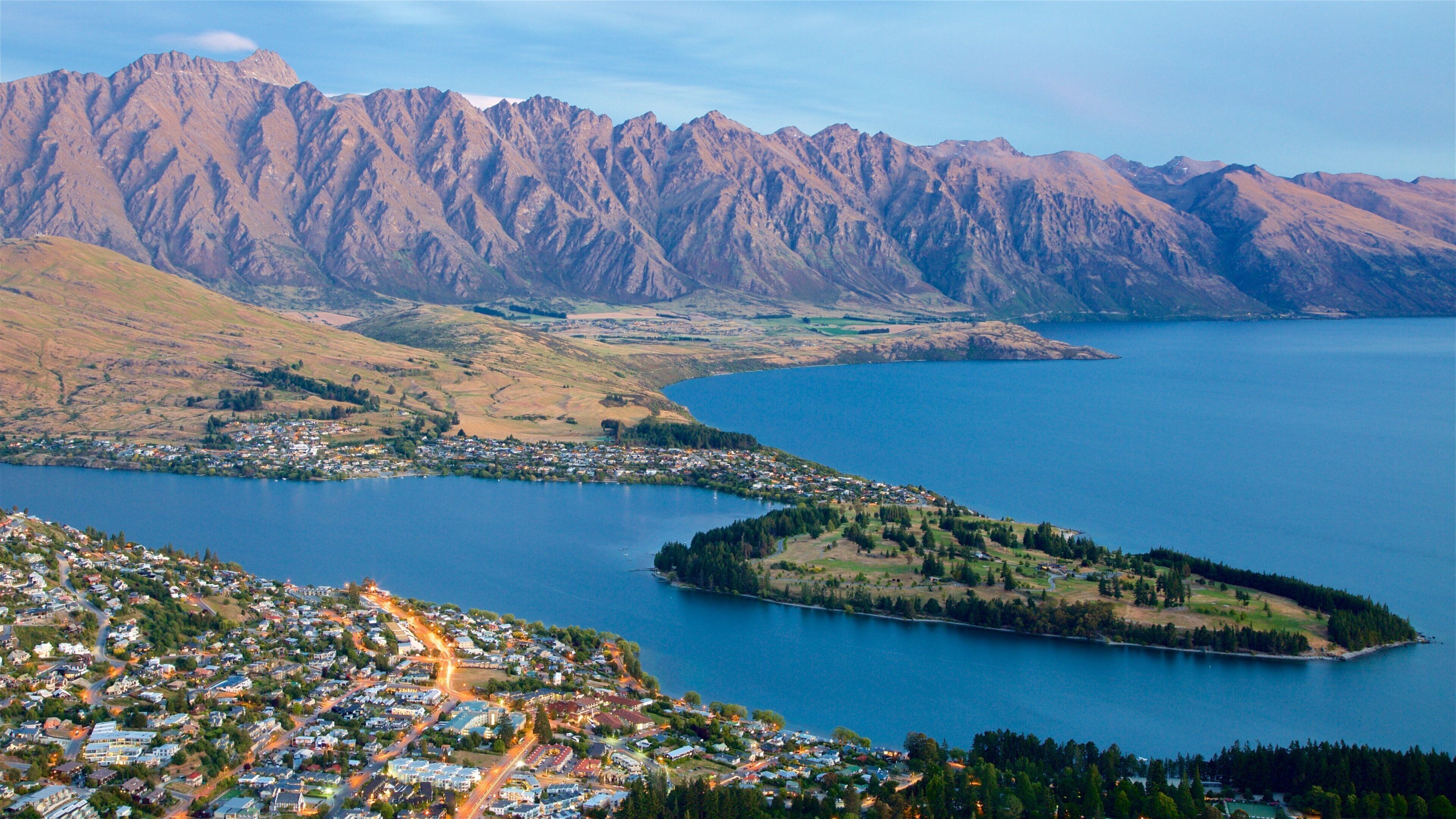 A coastal town with a mountain range in the background and a large body of water.