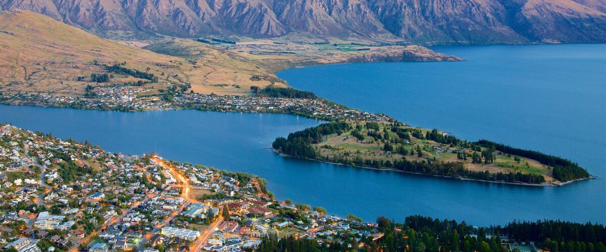A coastal town with a mountain range in the background and a large body of water.