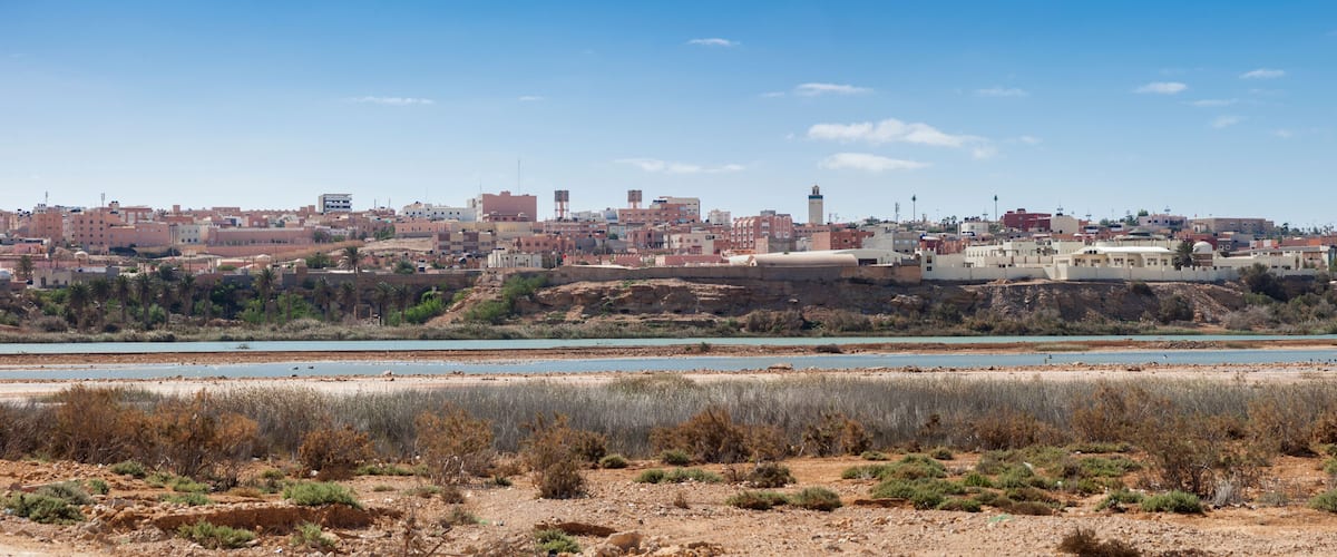 A coastal cityscape with buildings, a river, and a rocky shoreline.