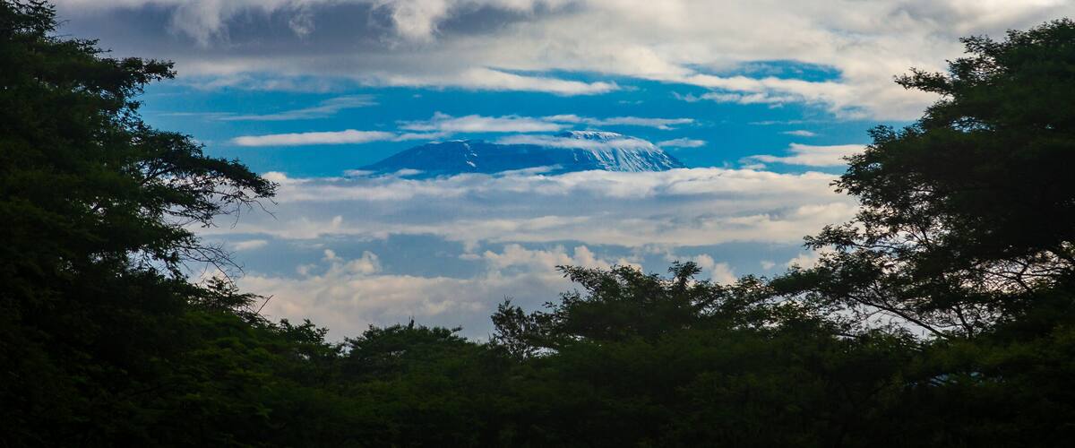 A mountain partially obscured by clouds with a clear blue sky above.