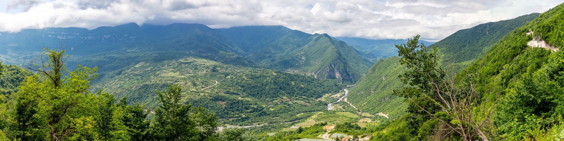 Tskhenistsqali river valley panorama in Racha region of Georgia with Svaneti mountain range, lush green forests and vineyards seen from to Khvamli Mountain.