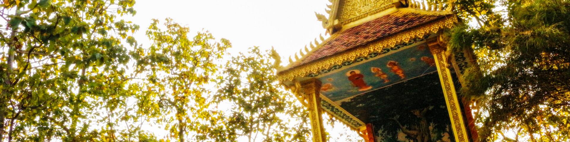 A temple with golden statues and intricate designs, surrounded by lush green trees.