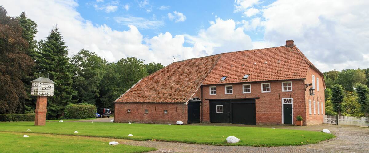A brick building with a tiled roof, a paved driveway, and a grassy area with white spherical objects.