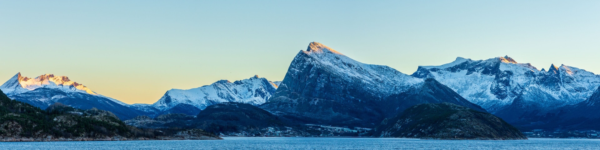 Schneebedeckte Berge, ein stiller See und ein klarer Himmel.