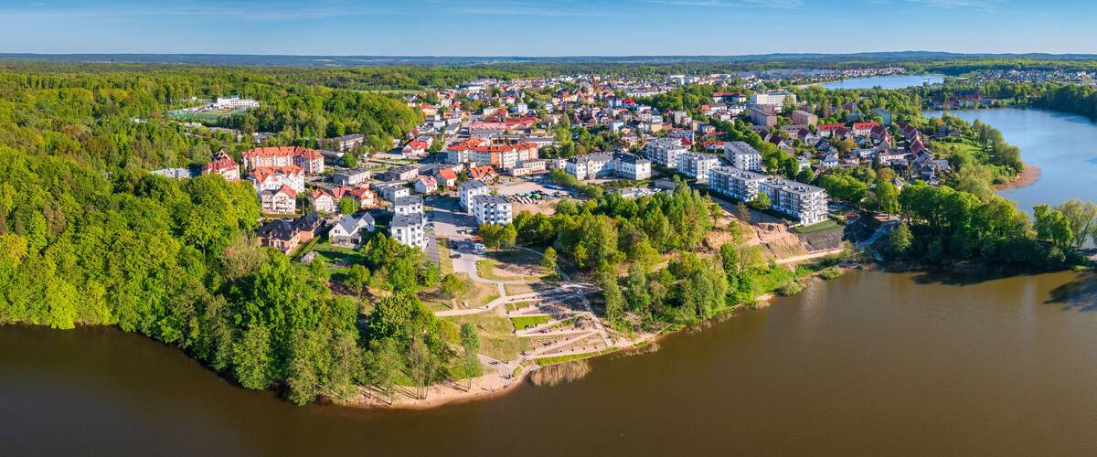 A river winding through a densely forested town with buildings along the riverbanks.