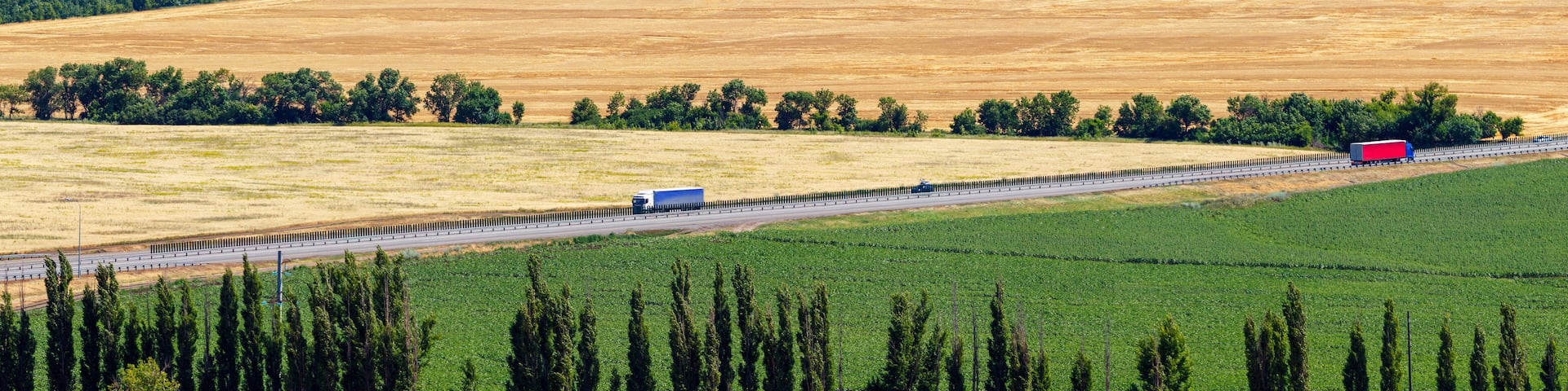 The panoramic aerial view of the highway among a farmland with trucks on it. Highway M4 "Don", Rostov-on-Don region, Russia