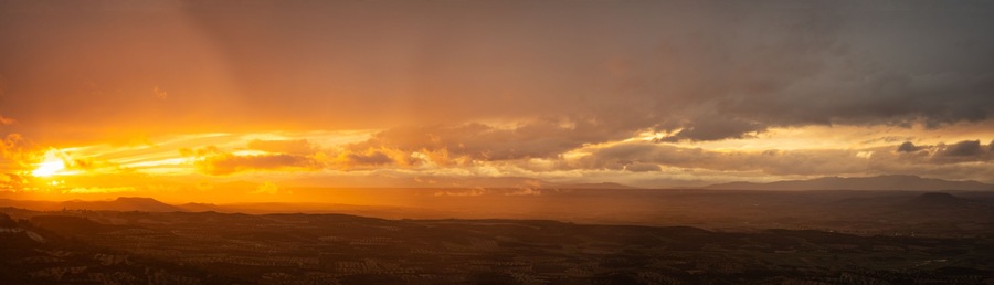 Ein Sonnenuntergang über einer Berglandschaft mit einem Tal darunter.