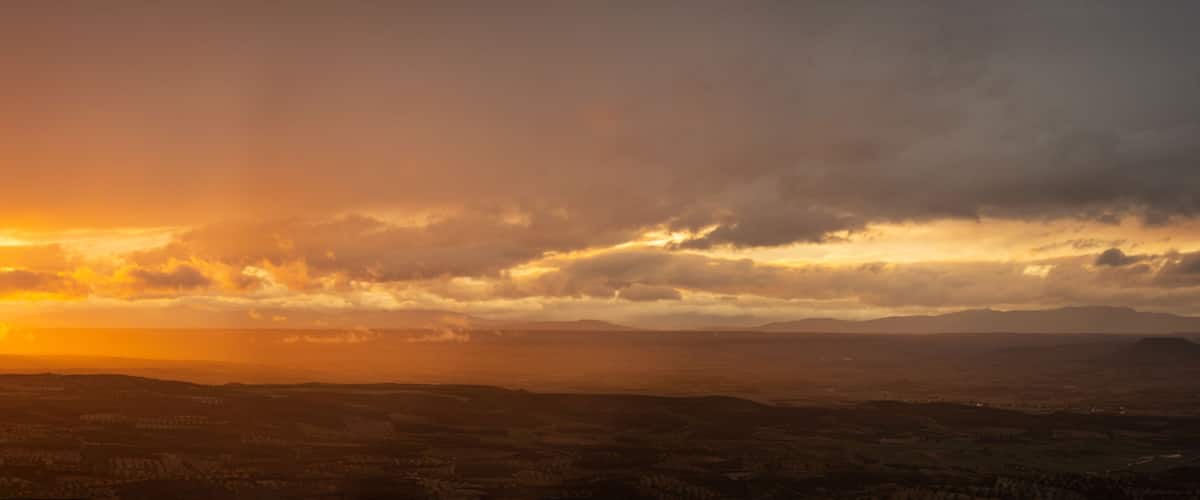 A sunset over a mountainous landscape with a valley below.