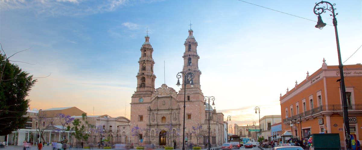 A historic church with two towers, a red taxi, and a clear sky.