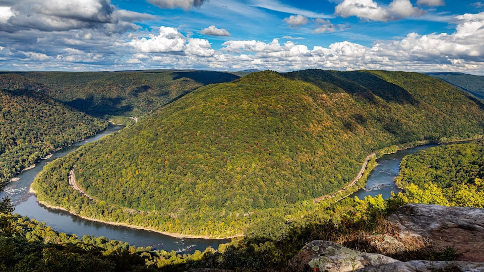 A river winding through a forested valley with mountains in the background.
