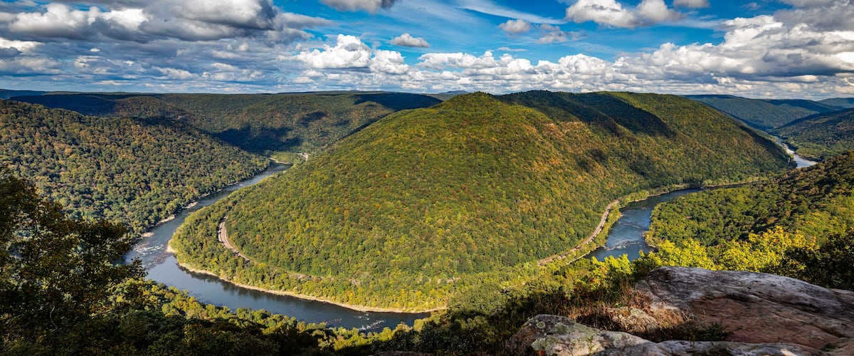 A river winding through a forested valley with mountains in the background.