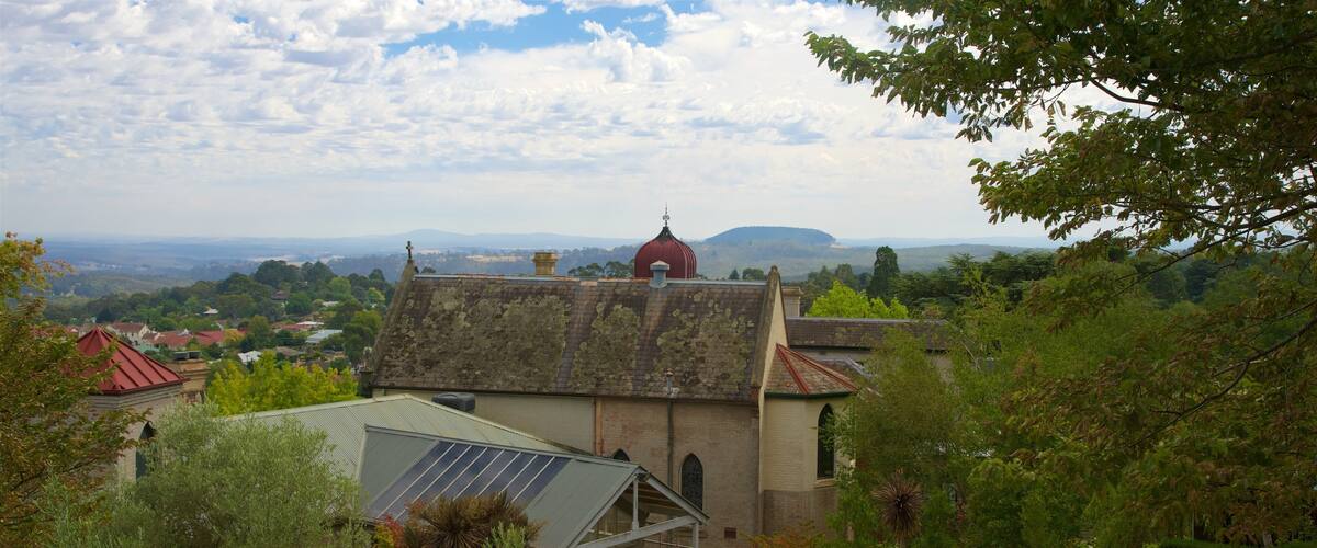 A church with a red dome, surrounded by lush greenery and a view of distant hills.