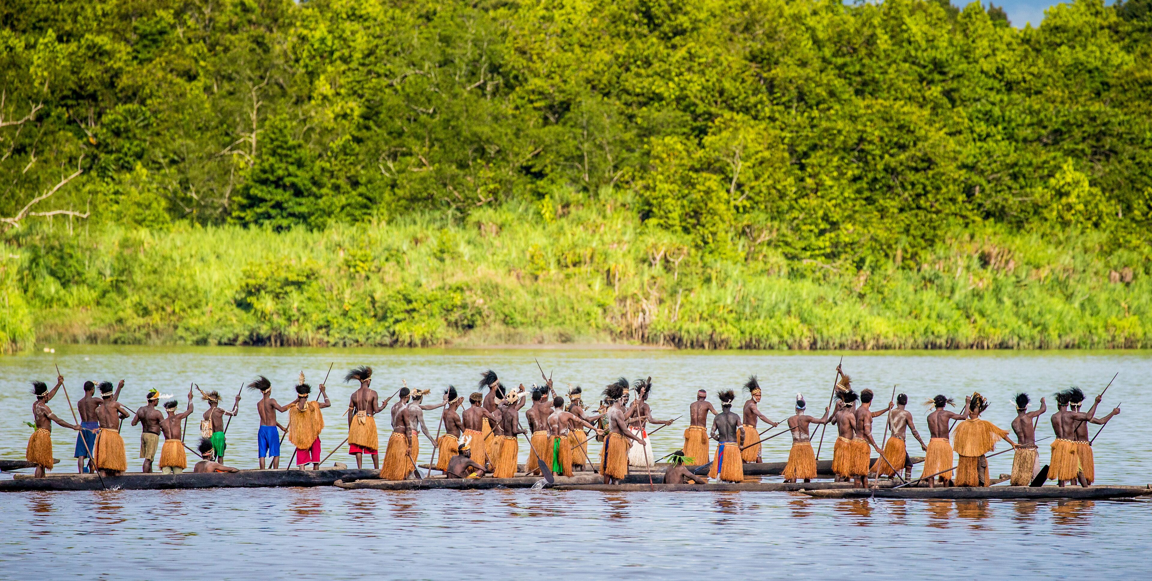 A group of people on a longboat in a river surrounded by lush greenery.