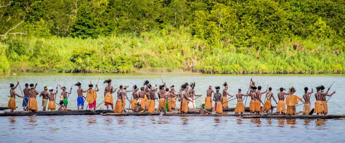 A group of people on a longboat in a river surrounded by lush greenery.