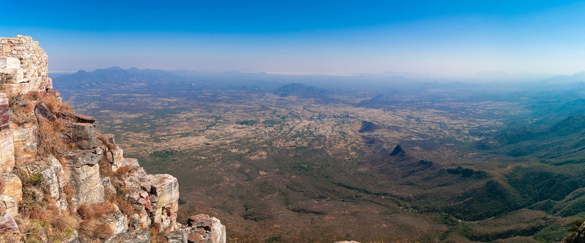 A mountainous landscape with a view of a valley and distant mountains.