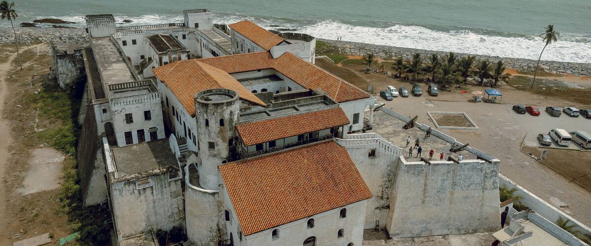 Aerial view of the Cape Coast Castle with its striking white walls and red-tiled roofs contrasting against the turquoise ocean, Cape Coast, Ghana.