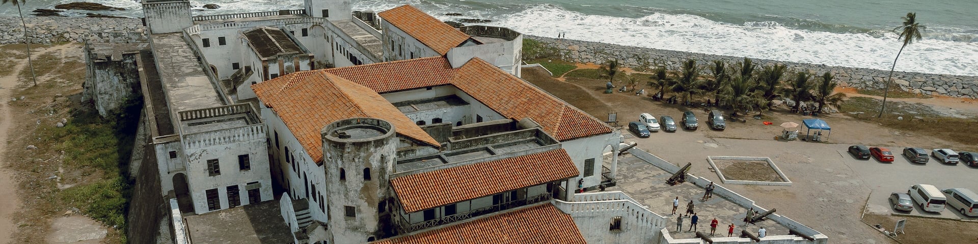Aerial view of the Cape Coast Castle with its striking white walls and red-tiled roofs contrasting against the turquoise ocean, Cape Coast, Ghana.