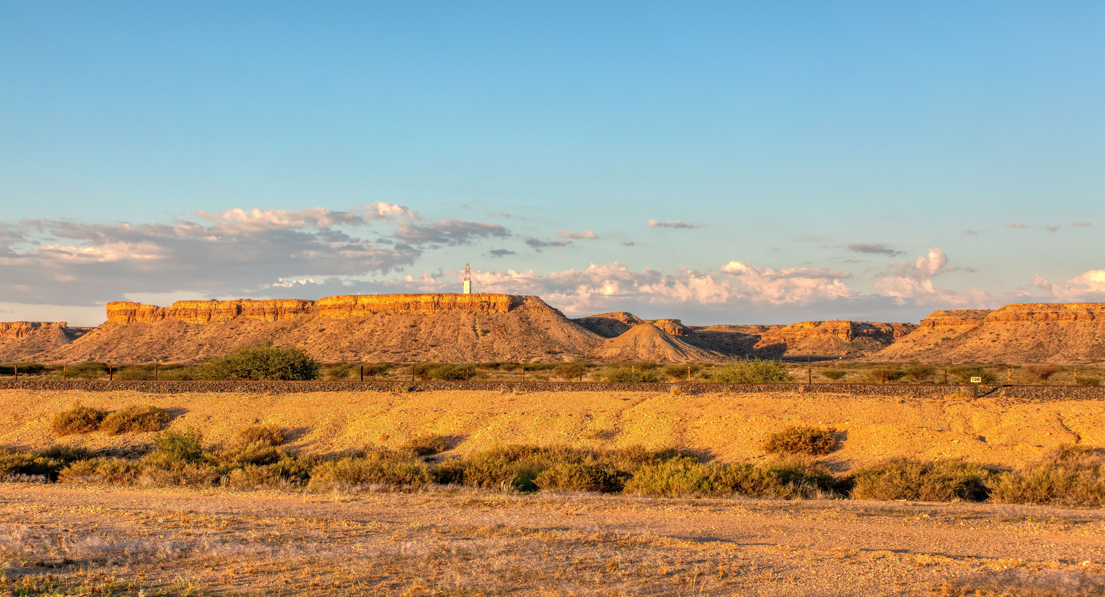A desert landscape with rocky formations and sparse vegetation under a clear sky.