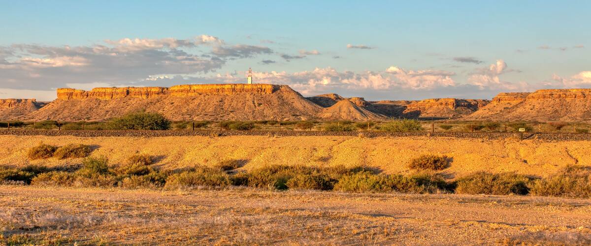 A desert landscape with rocky formations and sparse vegetation under a clear sky.