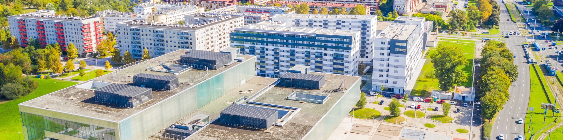 Paisagem urbana com edifícios modernos, um estacionamento e uma área verde do parque.