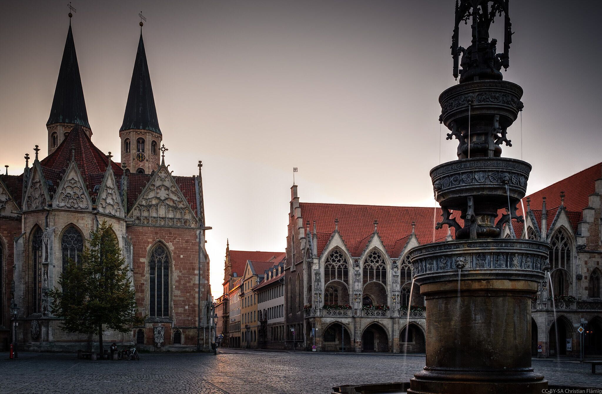 A historic church with twin spires and a Gothic-style fountain in the foreground.